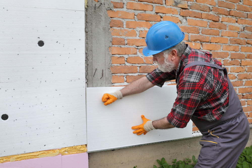 man brengt isolatie aan op buitenmuur